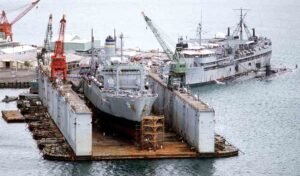 Gray ship inside a dry dock with cranes, part of an ABSD.