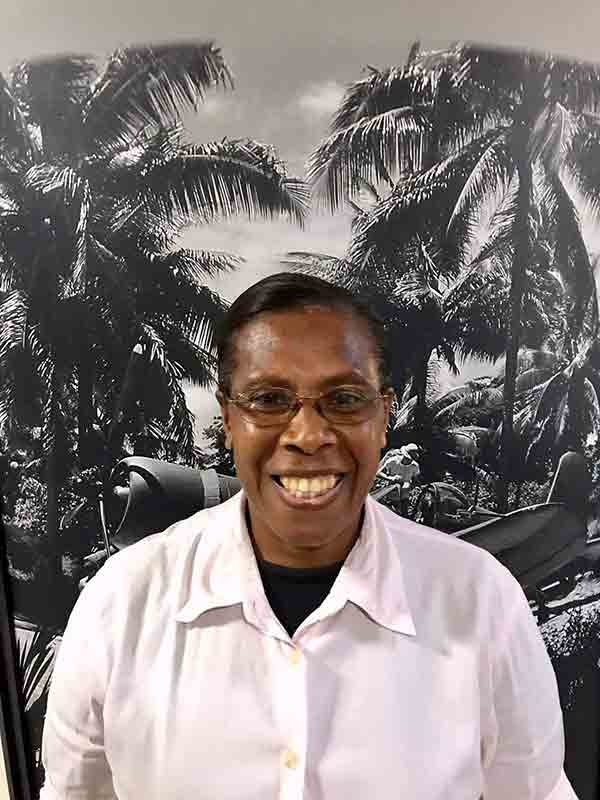 Museum team member smiling in front of a palm tree and airplane mural