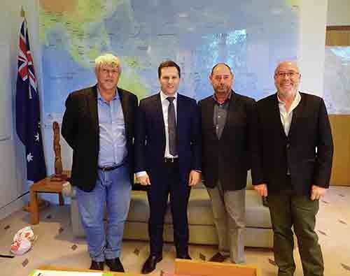 Four men stand in front of a large map during a Canberra trip.