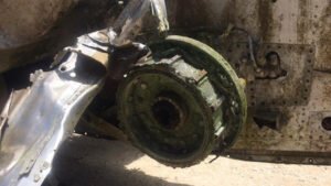 Close-up of a corroded aircraft wheel and brake assembly, showing signs of age and damage.