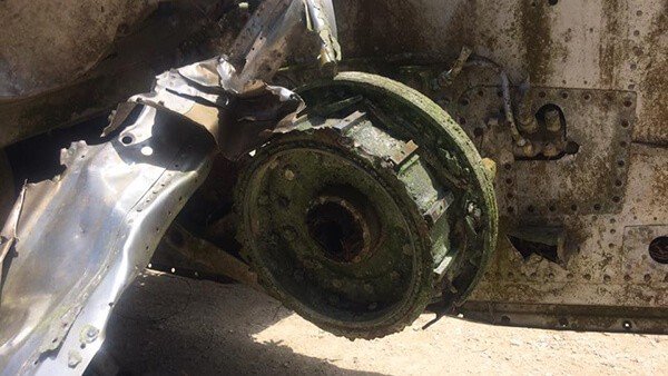 Close-up of a corroded aircraft wheel and brake assembly, showing signs of age and damage.
