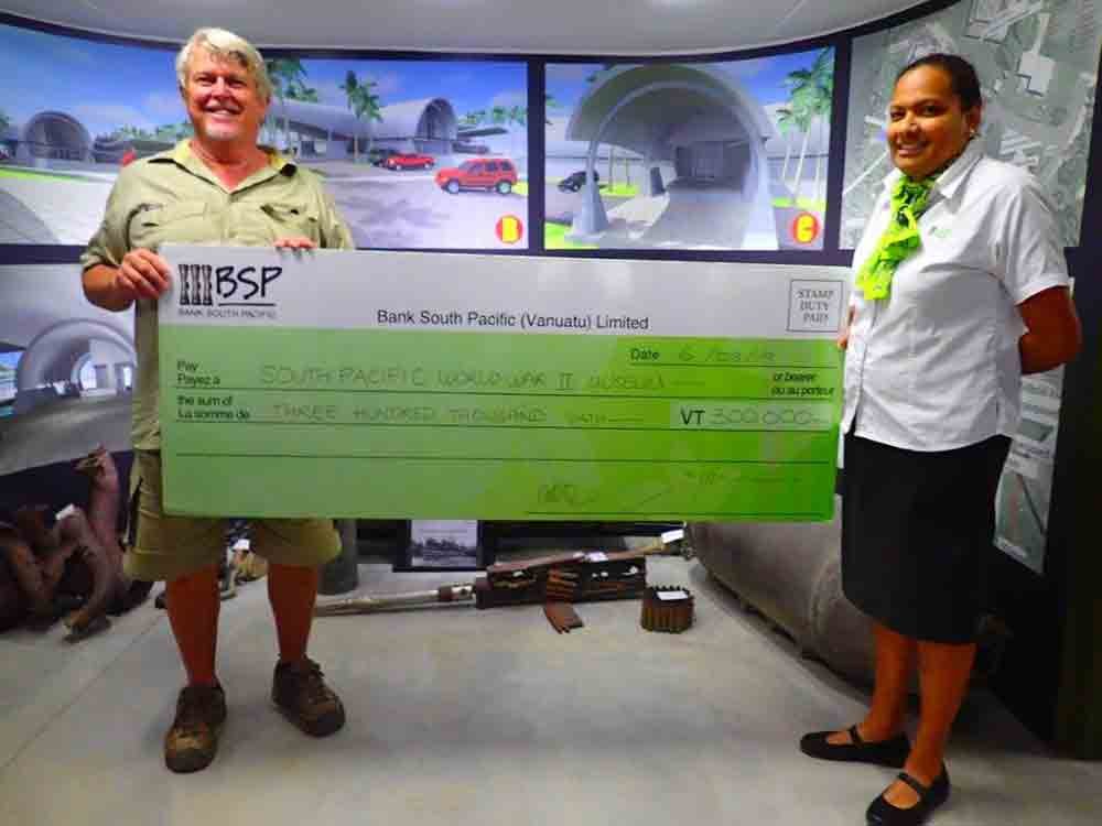 BSP Vanuatu sponsorship: Man and woman hold large check for South Pacific World War II Museum.