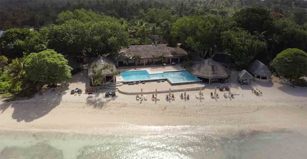 Breakas Beach Resort aerial view: beachfront bungalows, pool, and tropical gardens