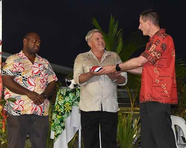 Three men in formal wear receiving an award at an event