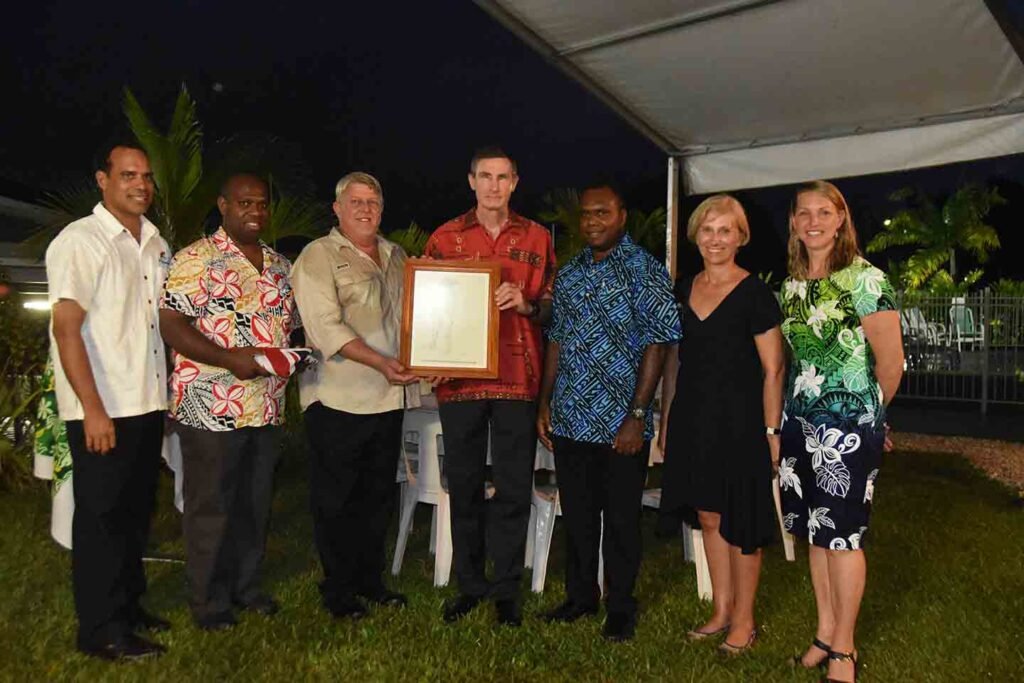 Group of people receiving an award in a nighttime outdoor ceremony