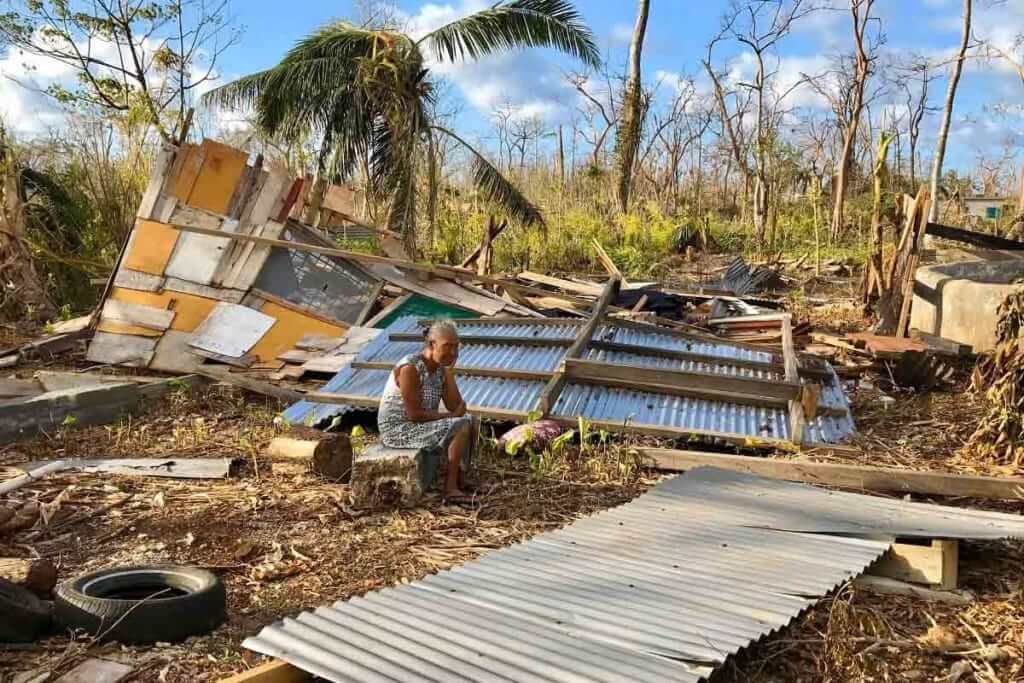 Elderly woman sits amidst the devastation of Cyclone Harold, her home destroyed.