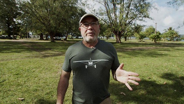 Man in t-shirt with airplane graphic talking outdoors