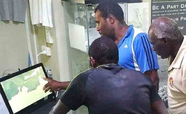 Three men looking at a computer screen displaying a map