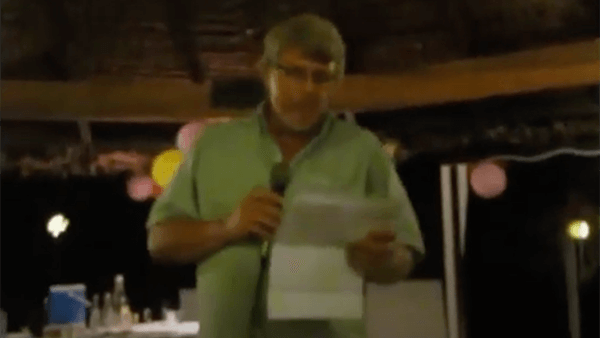 Man in green shirt speaking into microphone at event
