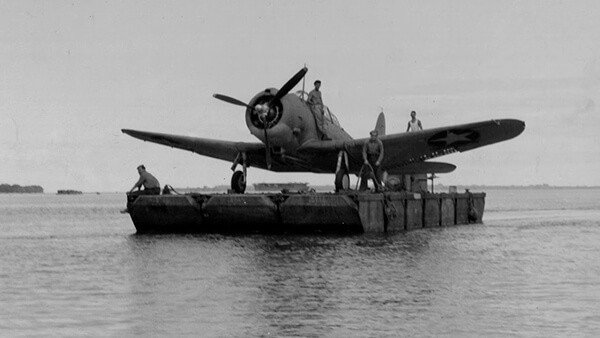 WWII US Navy floatplane on a barge, men aboard