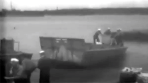 Black and white video footage of people on a boat.
