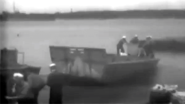 Black and white video footage of people on a boat.