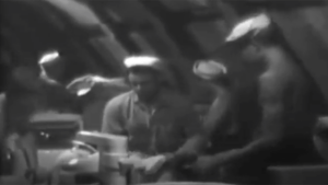 Men in a kitchen preparing food in a black and white video.