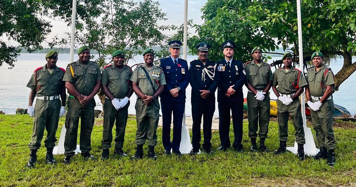 Veterans in uniform stand in a line outdoors, honoring Lest We Forget.