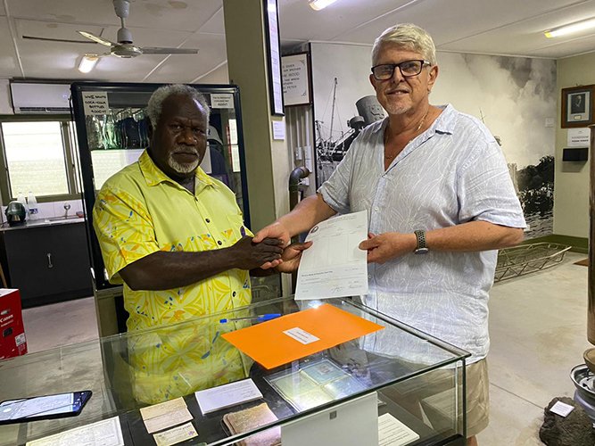 Two men shaking hands over a check, possibly a Reserve Bank funding transaction.