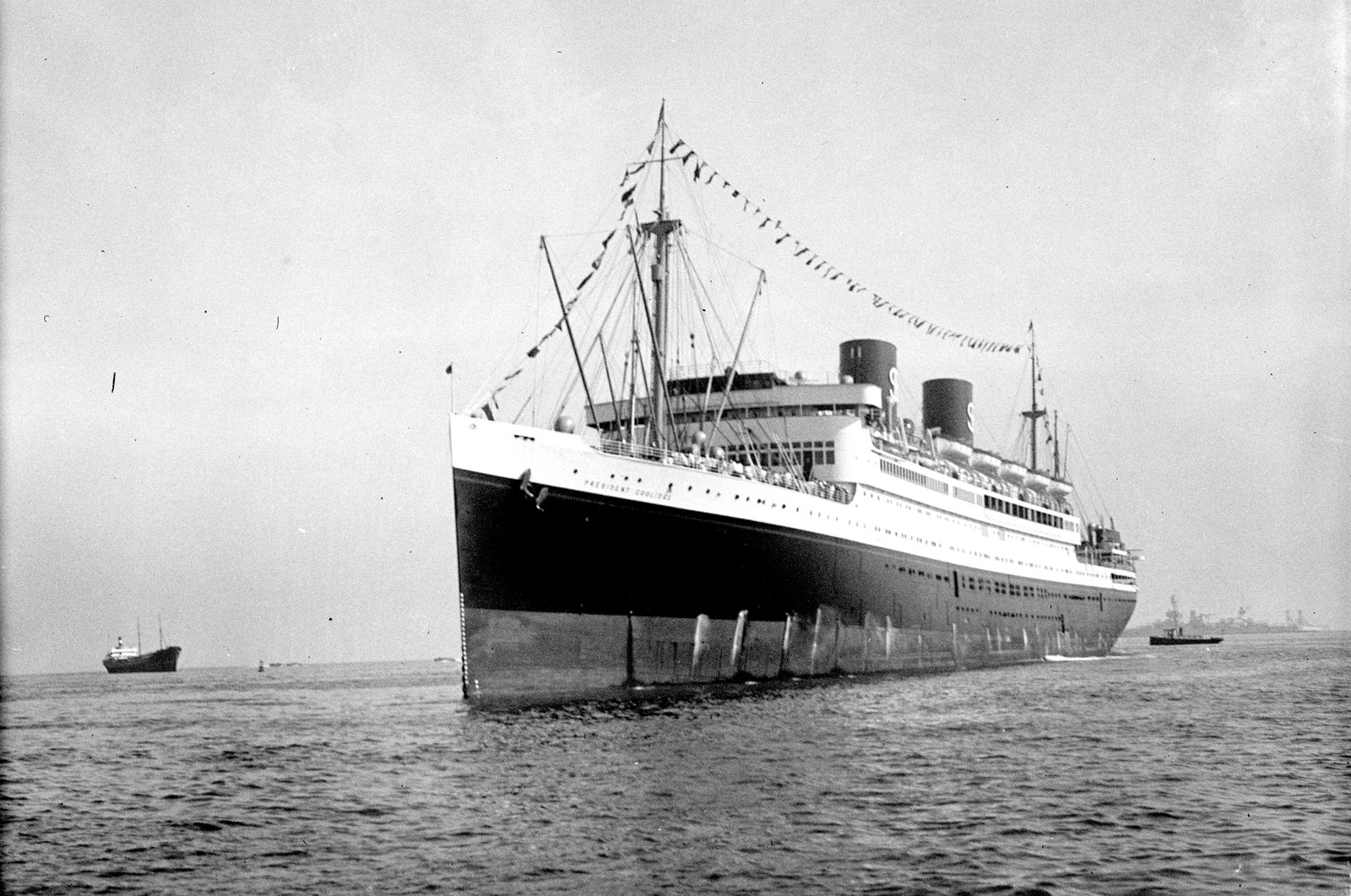 SS Normandie ocean liner sailing on the ocean, decorated with flags.
