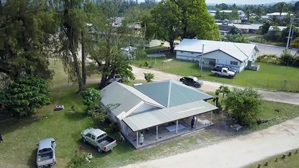 Aerial view of a village with houses, trees, and vehicles.