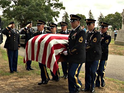 Pallbearers carry the casket of Elwood J Euart in a military funeral.