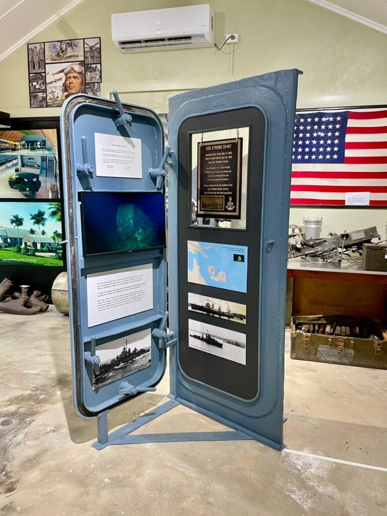 Naval history exhibit with ship door, photos, and maps